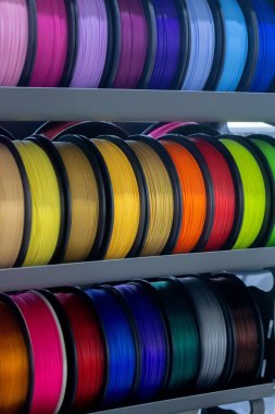 Üç boyutlu basım için çok renkli plastiğe sahip bir sürü makara. 3 boyutlu yazıcı için pembe, kırmızı, bordo, mor, sarı, turuncu, mavi plastik telli makaralar. 3 boyutlu yazdırma için bileşenler. 3B yazıcı için aksesuarlar