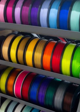 Üç boyutlu basım için çok renkli plastiğe sahip bir sürü makara. 3 boyutlu yazıcı için pembe, kırmızı, bordo, mor, sarı, turuncu, mavi plastik telli makaralar. 3 boyutlu yazdırma için bileşenler. 3B yazıcı için aksesuarlar