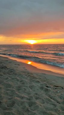 Denizde gün doğumu ya da gün batımı. Güneşin doğuşu ya da batışı ufukta belirdi. Kara yağmurlu bulutlarla gökyüzünde şafak. Gökyüzünde yağmurdan önce büyük bulutlarla gün batımı. Doğa arkaplanı. Doğal arkaplan dikey
