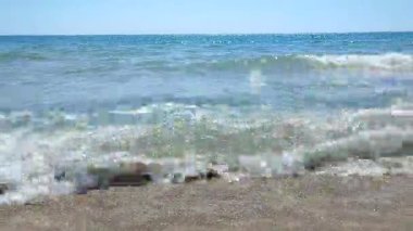 Turkuvaz şeffaf suyla güzel deniz dalgaları güneşli yaz gününde kumlu kumsalda yuvarlanıyor. Sessiz, sakin, rüzgarsız deniz. Düşük açı. Aşağıdan. Hiç kimse. Doğa arkaplanı. Doğal arkaplan