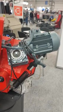 Kyiv, Ukrayna, 25 Haziran 2025: Büyük gri elektrikli motor şanzımana bağlı endüstriyel ekipmanın bir parçası. Kırmızı metal çanta. Millet, sergi ya da ticaret platformunda duruyor. Dikey