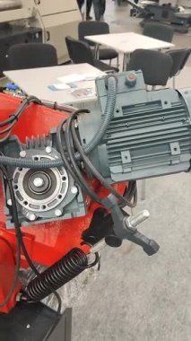 Büyük gri elektrikli motor şanzımana bağlı endüstriyel ekipmanın bir parçası. Kırmızı metal çanta. Millet, sergi ya da ticaret platformunda duruyor. Endüstriyel motor ekipman makinesi aygıtı