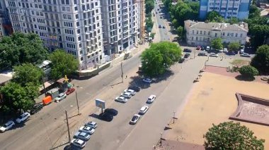 Odessa, Ukrayna, 12 Ağustos 2025, güneşli yaz gününde şehir caddesi. Hareket halindeki arabalar, tramvay rayları, meydan, yeşil ağaçlar, binalar, şehirde yürüyen insanlar. Şehir manzarası yukarıda. Üst görünüm