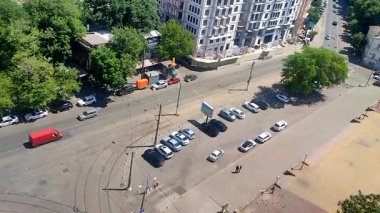 Odessa, Ukrayna, 12 Ağustos 2025: Şehir meydanı, binalar, yol, park edilmiş, hareket halindeki arabalar, yeşil ağaçlar ve güneşli yaz gününde yürüyen insanlar. Güneşli yaz gününde şehir caddesi. Şehir manzarası yukarıda. Üst görünüm