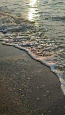 Gün batımında ya da denizde şafakta. Okyanusta gün batımı ya da gün doğumu. Deniz dalgalarında güneşli bir yol. Güneş, gökyüzü, bulutlar, deniz, deniz dalgaları, kumlu sahil, sahil. Sabah ve akşam sahilde. Dikey