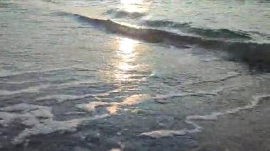 Gün batımında ya da denizde şafakta. Okyanusta gün batımı ya da gün doğumu. Deniz dalgalarında güneşli bir yol. Güneş, gökyüzü, bulutlar, deniz, deniz dalgaları, kumlu sahil, sahil. Sabah ve akşam sahilde.