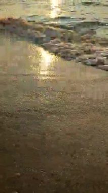 Deniz dalgalarının yüzeyi güneş yollarıyla sabah gündoğumunda. Okyanusun karanlık suları akşam vakti dalgalanır. Deniz kıyısında. Soyut doğal arkaplan. Hareket eden su arka planı. Dikey