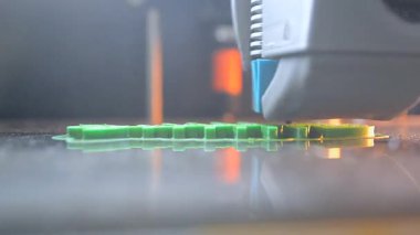3D yazıcı bir nesne yazdırıyor. Bir 3D yazıcı, 3D yazıcının çalışma yüzeyine erimiş plastikten bir nesne basıyor. Bir 3D yazıcı bir model yaratıyor. Erimiş plastiğin yakın plan ekstrakderden akışı.