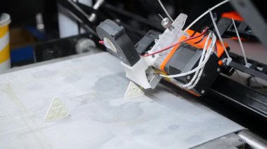 3D yazıcı bir nesne yazdırıyor. Bir 3D yazıcı, 3D yazıcının çalışma yüzeyine erimiş plastikten bir nesne basıyor. Bir 3D yazıcı bir model yaratıyor. Erimiş plastiğin yakın plan ekstrakderden akışı.