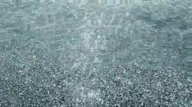 Sığ kumlu sahilde şeffaf temiz su ve güneşli yaz gününde deniz kabukları. Güneş suyun yüzeyinde parlıyor. Deniz kıyısında küçük dalgalar. Doğa arkaplanı. Doğal arkaplan.