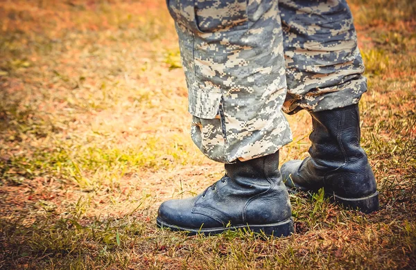 Homem fica em botas e calças militares — Fotografia de Stock