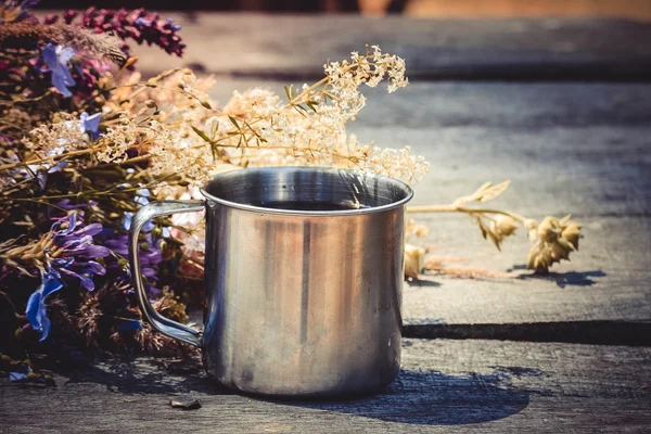 Steel mug of tea on the table and fresh flowers, — Stock Photo, Image