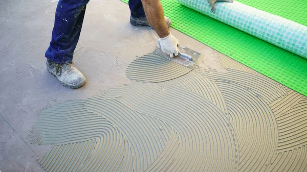 worker applying tile adhesive glue on the floor