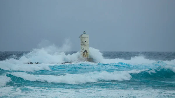 The lighthouse of the Mangiabarche shrouded by the waves of a mistral wind storm