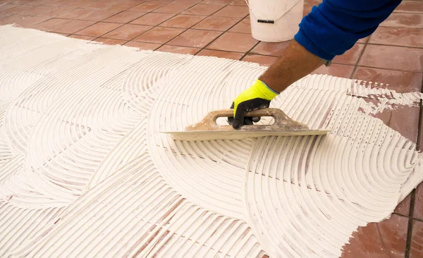 worker applying tile adhesive glue on the floor