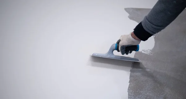 Beton zemine beyaz poliüretan reçinesi boyayan işçiler