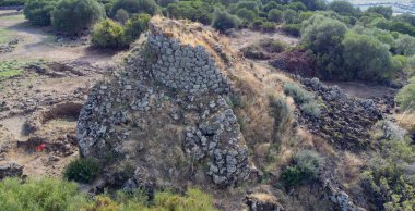 View of the Nuraghe Iloi archaeological site in Sedilo, Sardinia, featuring ancient basalt stone walls and panoramic landscape
