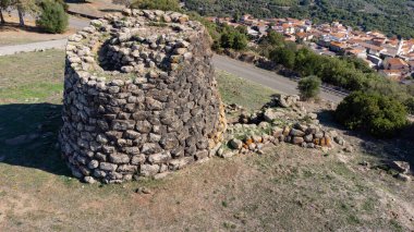 View of the Nuraghe Sa Jua archaeological site in Aidomaggiore, Sardinia, with basalt stones and surrounding countryside