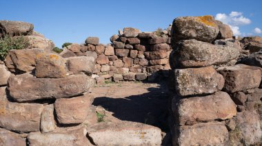 İtalya 'nın Sardunya kentindeki bir Nuraghe taş yapısının arkeolojik kalıntıları, yabani bitki örtüsüyle çevrili.