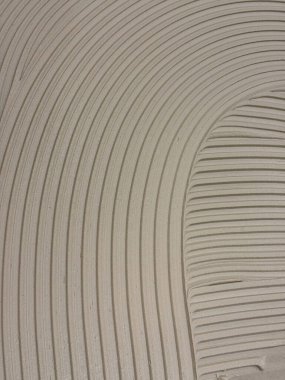 Yapışkan harç kıvrımlı çizgilerle yayılmış soyut desenli desen oluşturuyor