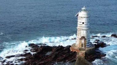 Mangiabarche Deniz Feneri kayalık kayalıklarda. Etrafı dalgalarla çevrili.