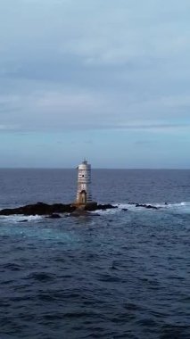 Açık denizle çevrili kayalık kayalıklarda duran yalnız deniz feneri.