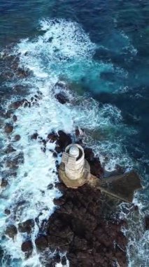 Açık denizle çevrili kayalık kayalıklarda duran yalnız deniz feneri.