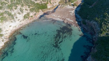 Uçurumlar ve kristal berrak deniz olan tenha turkuaz körfezin insansız hava aracı görüntüsü.