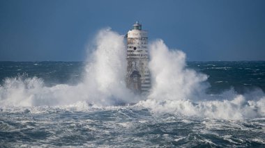 Güçlü fırtına dalgaları, ıssız bir deniz fenerine çarpıyor. Açık deniz koşullarında duruyor..