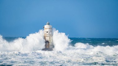 Güçlü fırtına dalgaları, ıssız bir deniz fenerine çarpıyor. Açık deniz koşullarında duruyor..