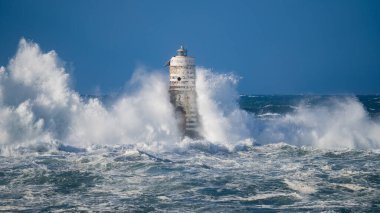 Güçlü fırtına dalgaları, ıssız bir deniz fenerine çarpıyor. Açık deniz koşullarında duruyor..