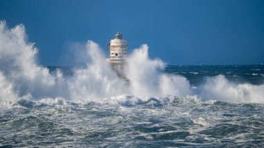 Güçlü fırtına dalgaları, ıssız bir deniz fenerine çarpıyor. Açık deniz koşullarında duruyor..