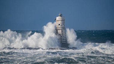 Güçlü fırtına dalgaları, ıssız bir deniz fenerine çarpıyor. Açık deniz koşullarında duruyor..