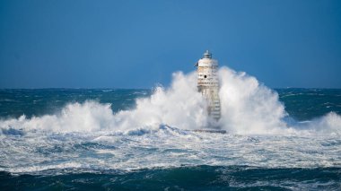 Güçlü fırtına dalgaları, ıssız bir deniz fenerine çarpıyor. Açık deniz koşullarında duruyor..