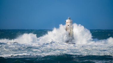 Güçlü fırtına dalgaları, ıssız bir deniz fenerine çarpıyor. Açık deniz koşullarında duruyor..