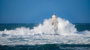 Güçlü fırtına dalgaları, ıssız bir deniz fenerine çarpıyor. Açık deniz koşullarında duruyor..