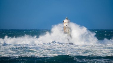 Güçlü fırtına dalgaları, ıssız bir deniz fenerine çarpıyor. Açık deniz koşullarında duruyor..
