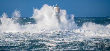 Güçlü fırtına dalgaları, ıssız bir deniz fenerine çarpıyor. Açık deniz koşullarında duruyor..