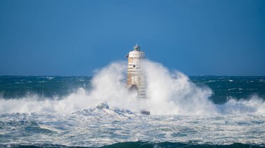 Güçlü fırtına dalgaları, ıssız bir deniz fenerine çarpıyor. Açık deniz koşullarında duruyor..