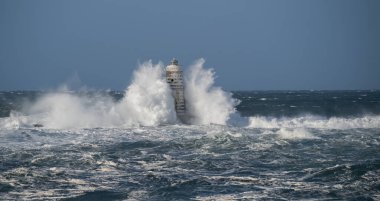 Güçlü fırtına dalgaları, ıssız bir deniz fenerine çarpıyor. Açık deniz koşullarında duruyor..