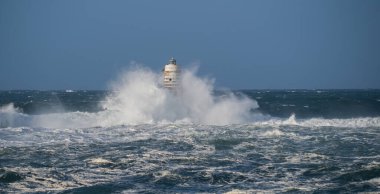 Güçlü fırtına dalgaları, ıssız bir deniz fenerine çarpıyor. Açık deniz koşullarında duruyor..