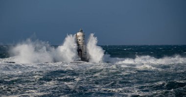 Güçlü fırtına dalgaları, ıssız bir deniz fenerine çarpıyor. Açık deniz koşullarında duruyor..