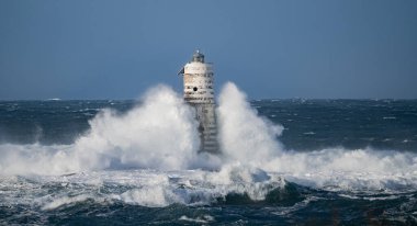 Güçlü fırtına dalgaları, ıssız bir deniz fenerine çarpıyor. Açık deniz koşullarında duruyor..