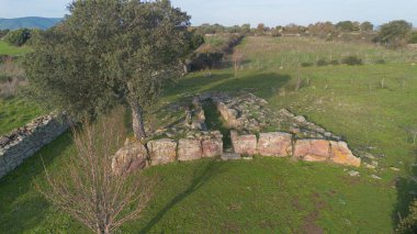 Sardunya 'nın yeşil kırsal kesimleriyle çevrili antik bir Dev Mezar arkeolojik sahasının havadan görünüşü.