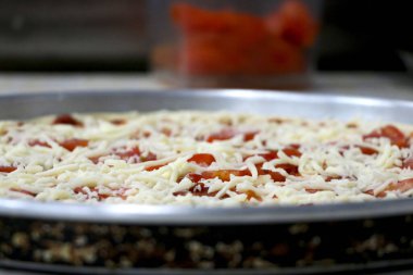 Pizza soslu, domatesli ve peynirli pizza hazırlama portresi.