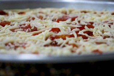 Pizza soslu, domatesli ve peynirli pizza hazırlama portresi.
