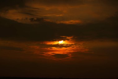 Gün batımında gökyüzünde saklanan güneşin dramatik görüntüsü