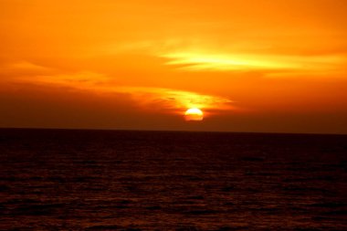 Sahilde gün batımı manzarası ve su yansıması.