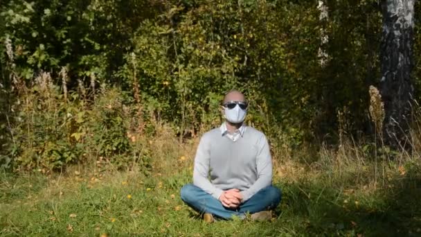 Férfi ül egy védő maszk az erdőben, magány koncepció — Stock videók