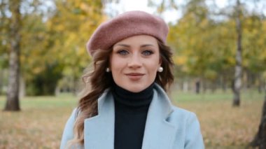 Sonbahar parkında gülümseyen zarif bir kız portresi.